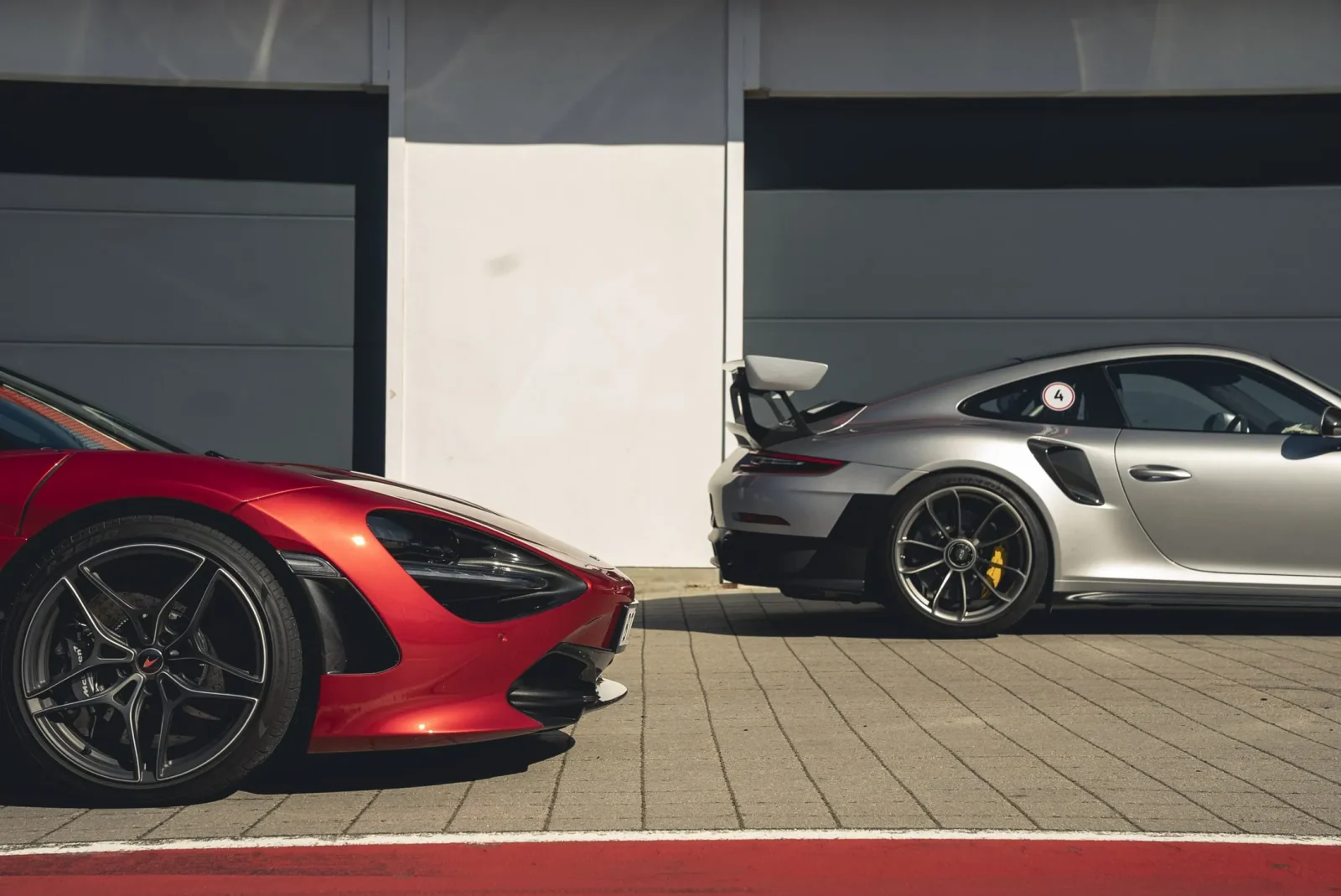 Rød og sølvfarget supersportsbil parkert utenfor depot på racerbane