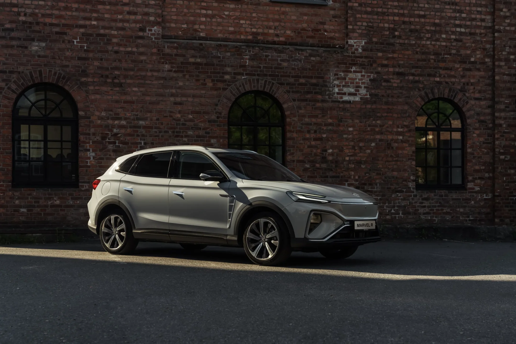 Lys SUV parkert foran murbygg med buede vinduer